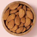 Wooden bowl filled with almonds on a pink background healthy snacking UK