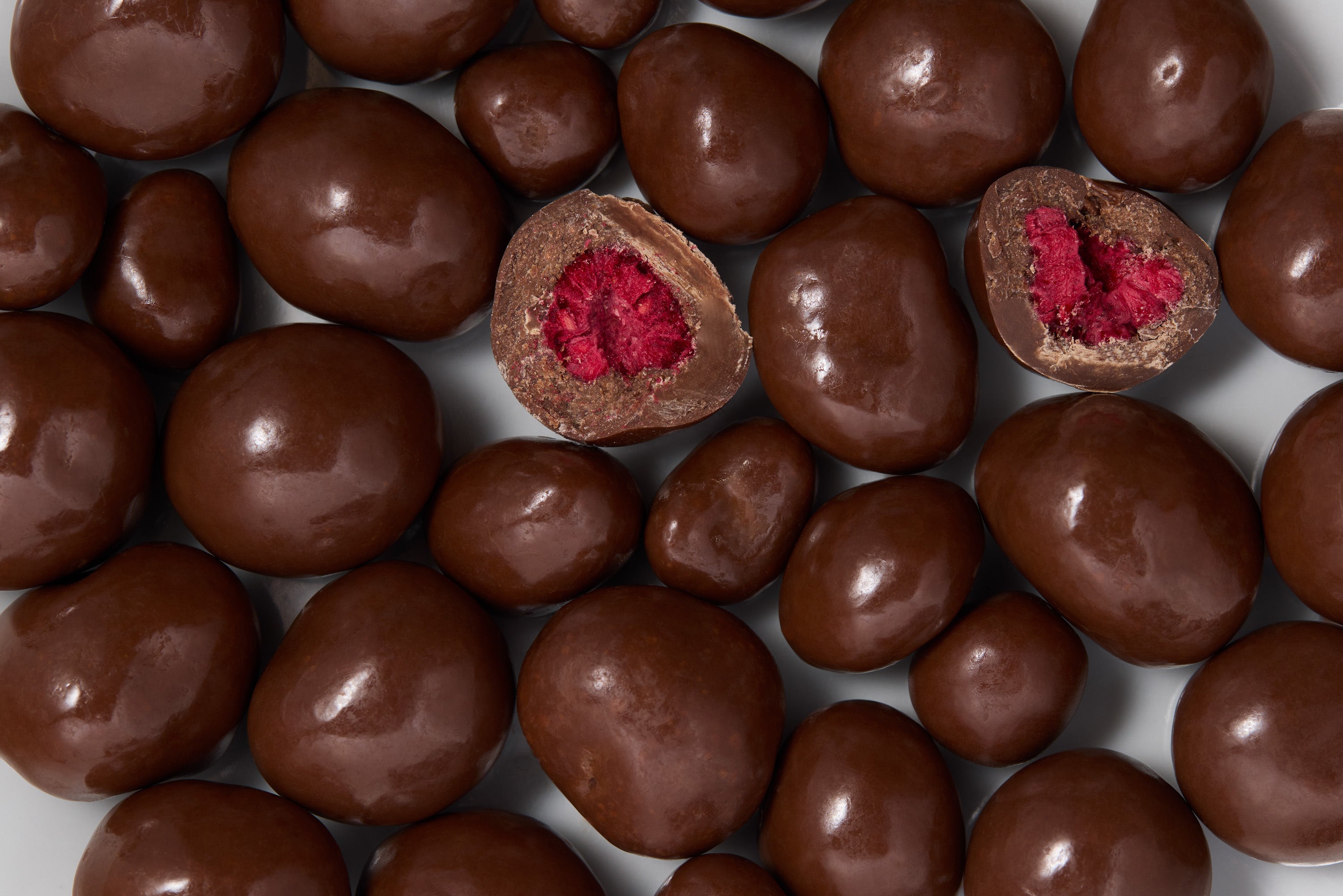 Chocolate-covered raspberries with a red center on a white background