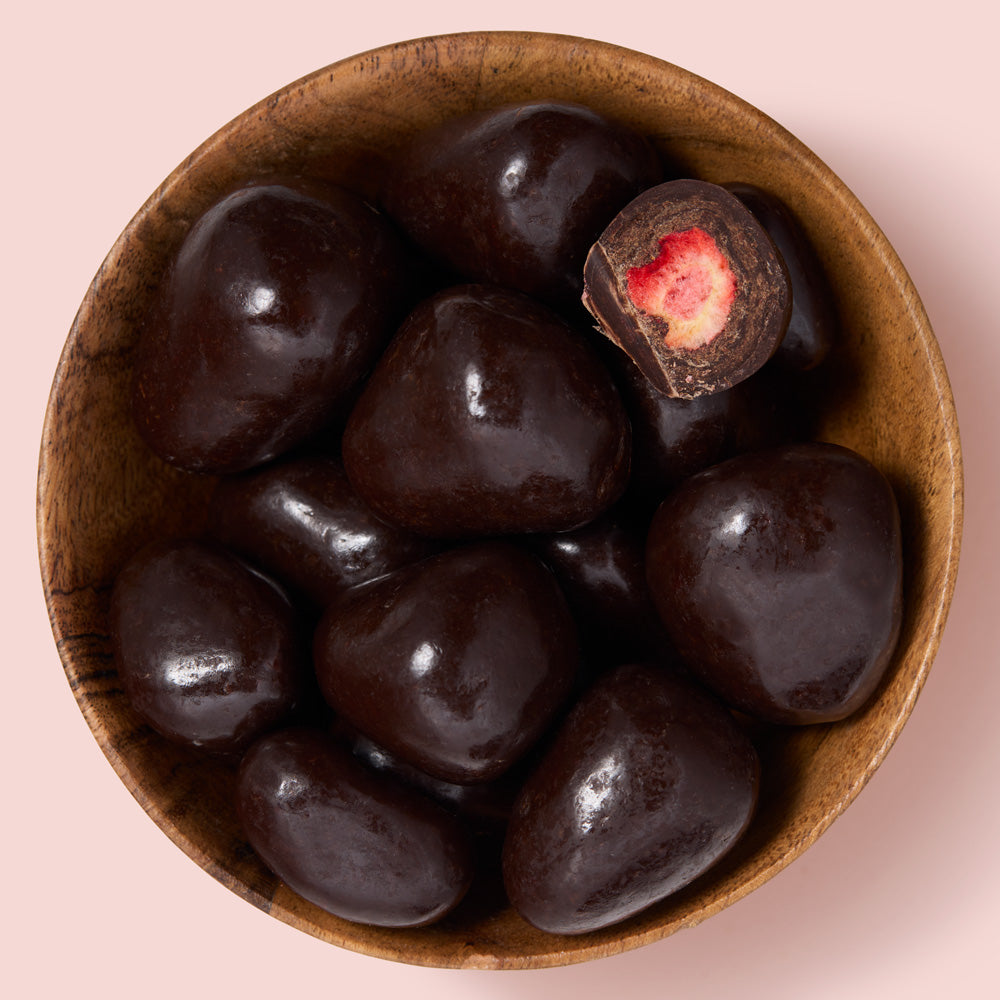 Wooden bowl filled with dark chocolate-strawberries on a pink background healthy snacking UK