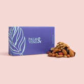 Blue box labeled 'Palm & Vine' with a pile of mixed nuts and fruit on a pink background healthy snacking UK