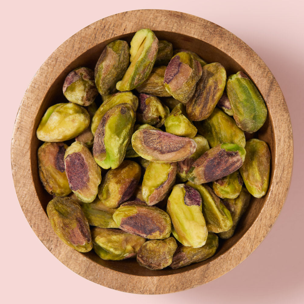 Pistachios in a wooden bowl on a pink background healthy snacking UK