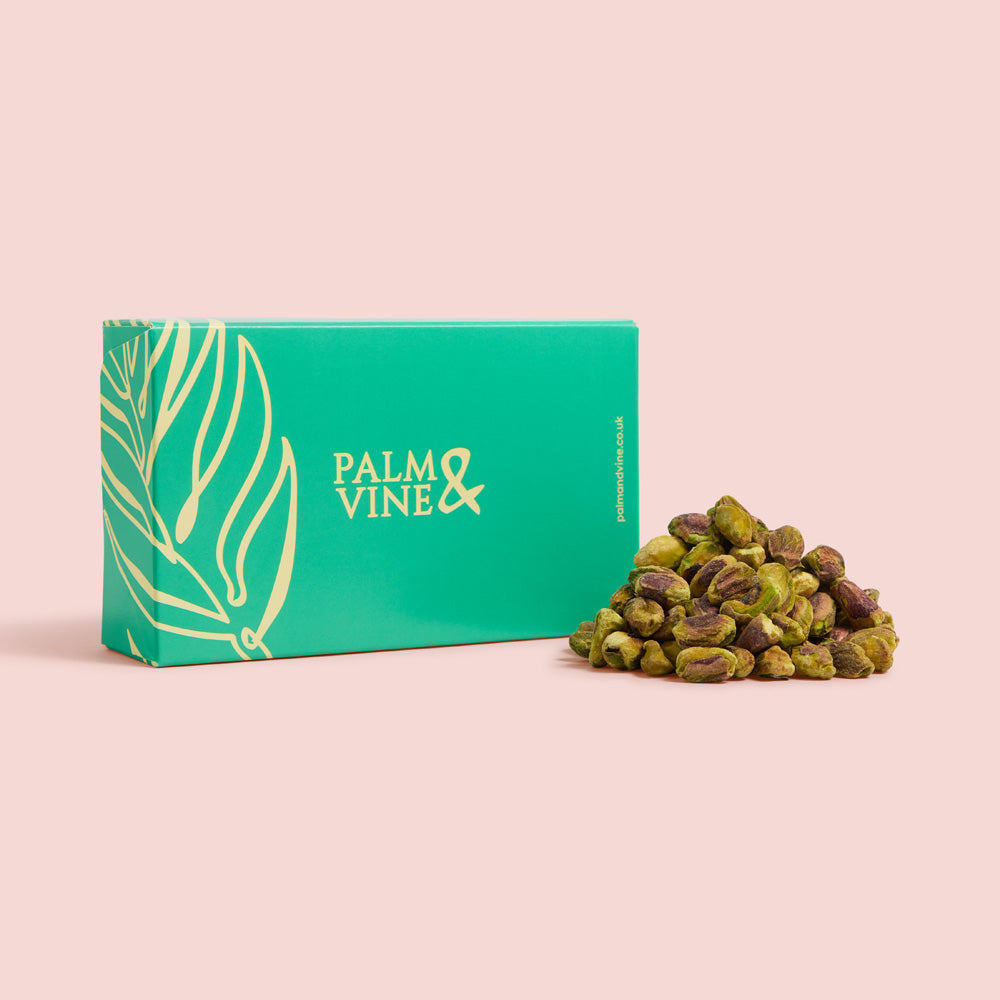 Green box with 'Palm & Vine' branding next to a pile of green pistachios on a pink background healthy snacking UK