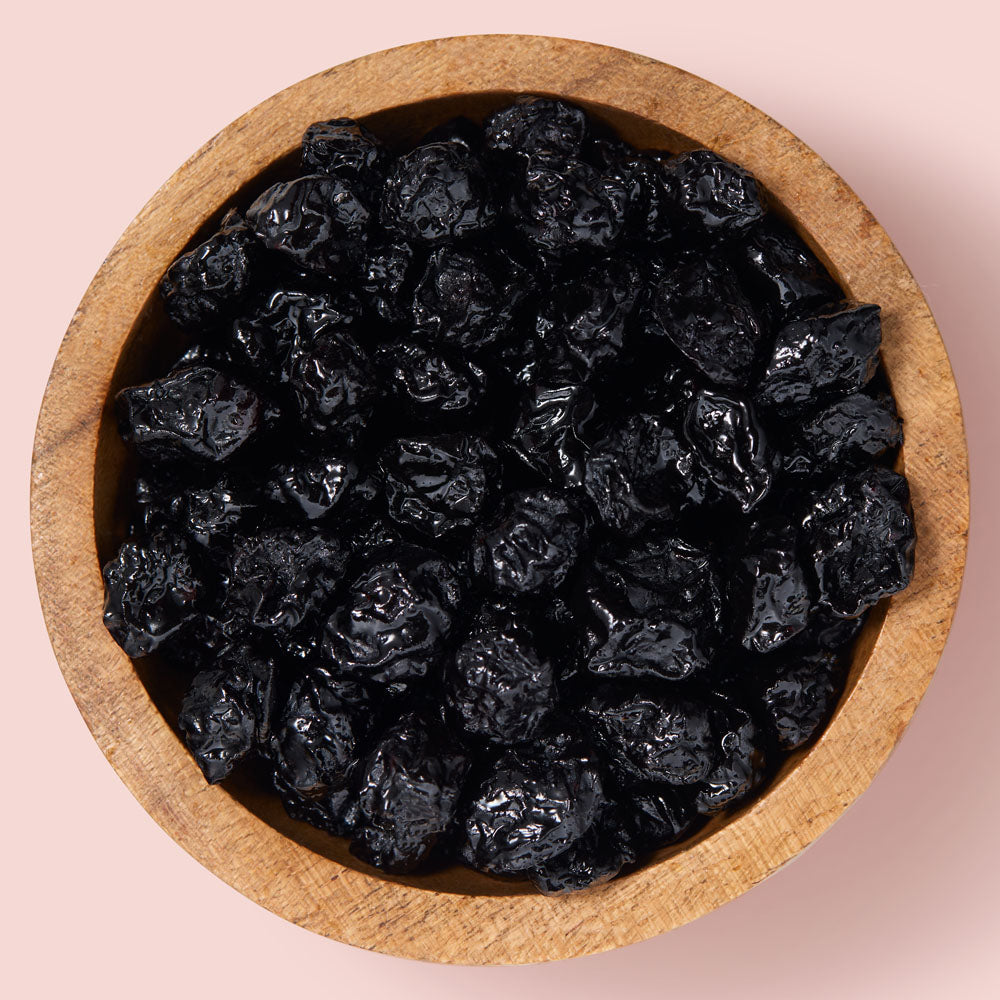 Wooden bowl filled with dried blueberries on a pink background healthy snacking UK