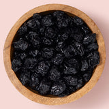 Wooden bowl filled with dried blueberries on a pink background healthy snacking UK