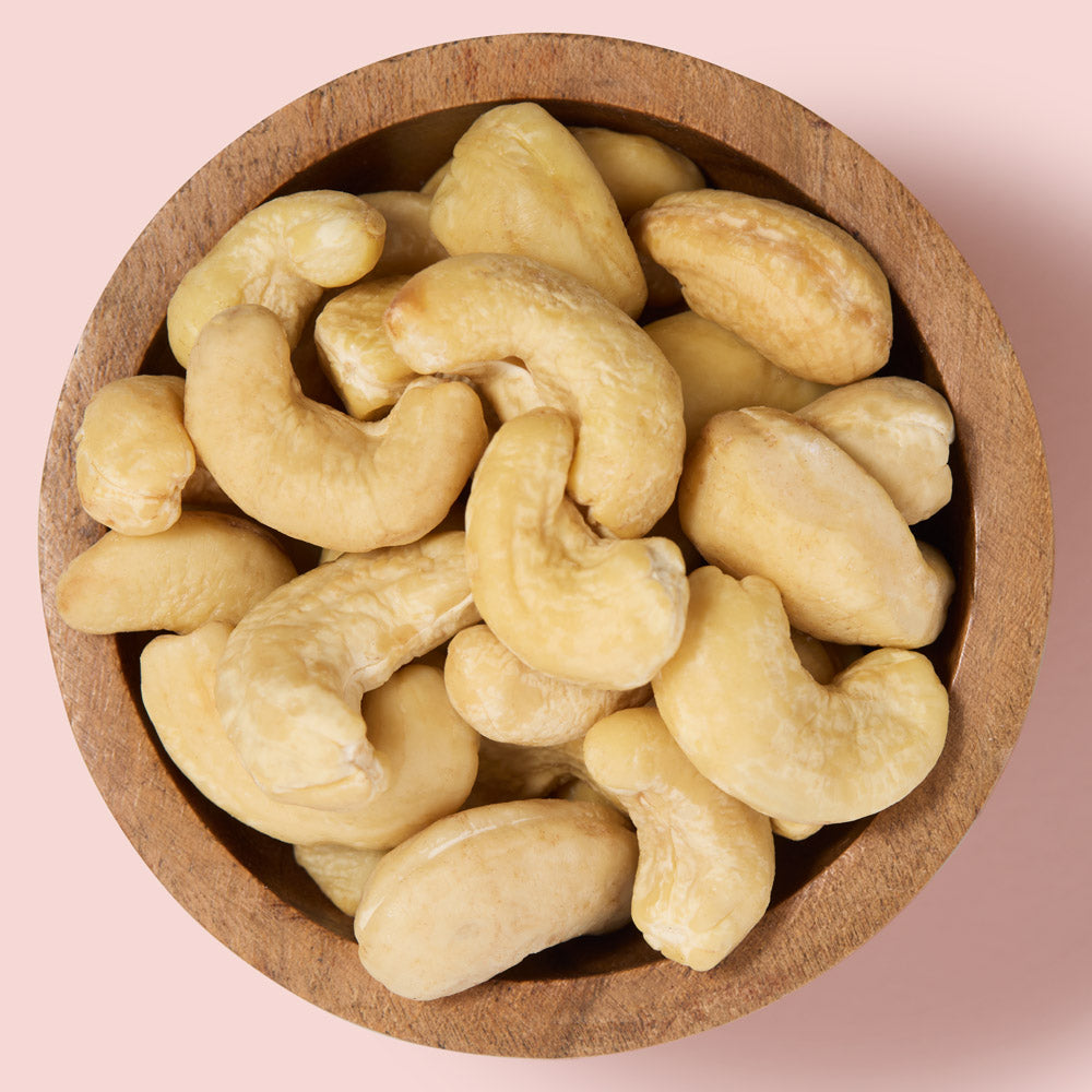Cashews in a wooden bowl on a pink background  healthy snacking UK