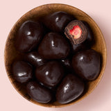 Wooden bowl filled with dark chocolate-strawberries on a pink background  healthy snacking UK