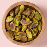 Pistachios in a wooden bowl on a pink background  healthy snacking UK