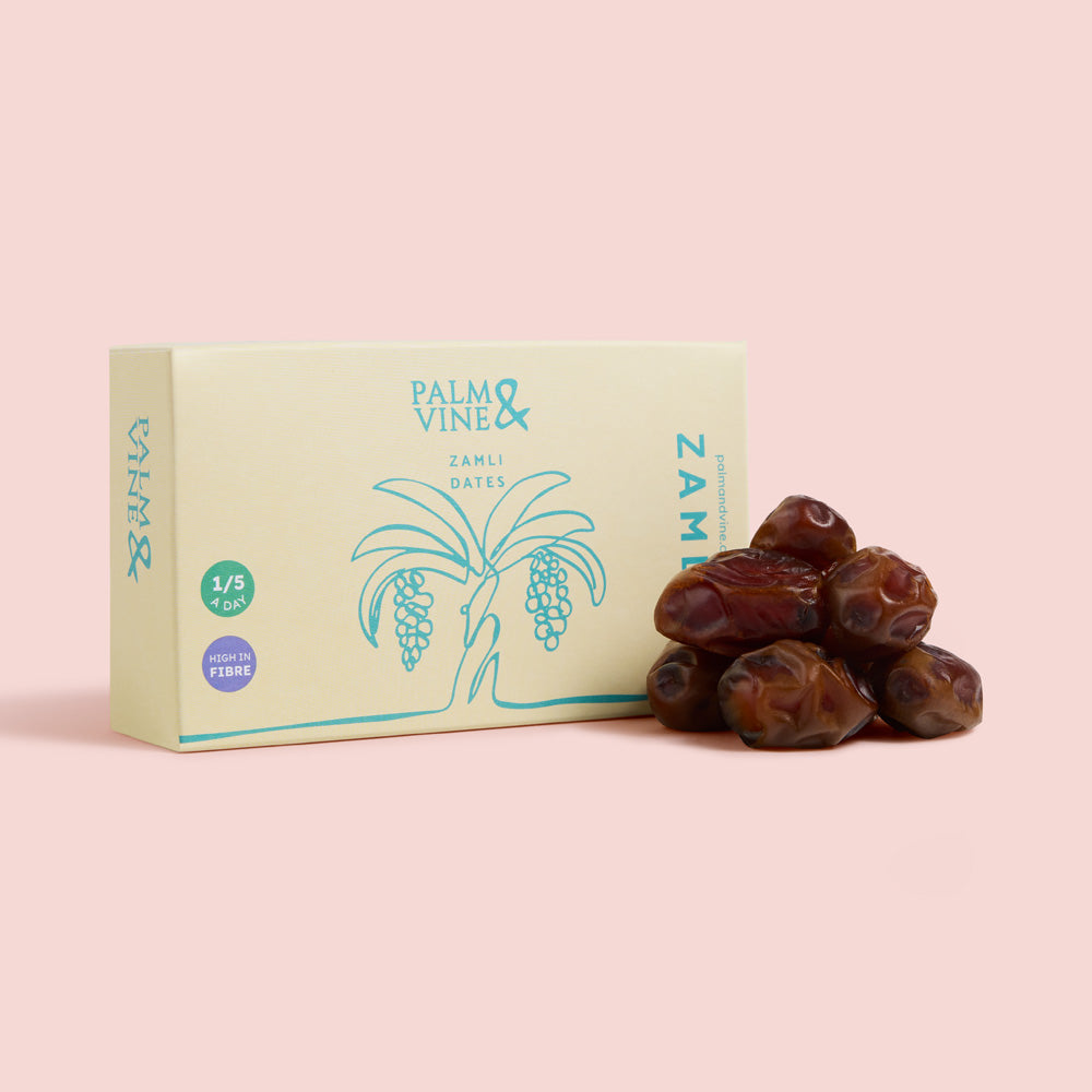 Box of Palm & Vine Zamli dates with dates on a pink background healthy snacking UK